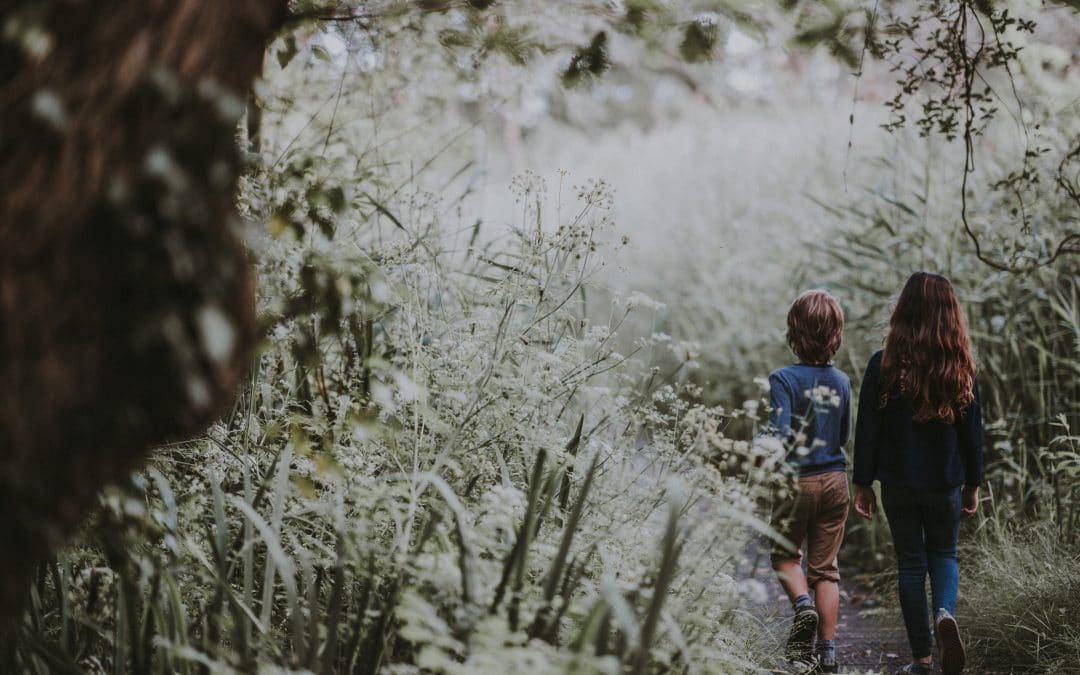girl and boy walking on forest trail